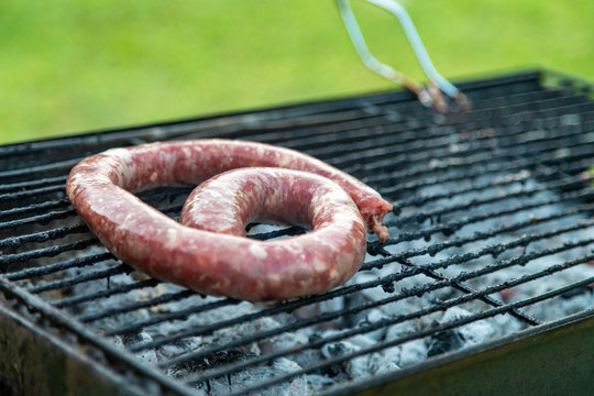 Grilling sausage on barbecue grill, BBQ in the garden
