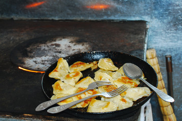 Russian dumplings with grilled crust in a pan on a fire stove