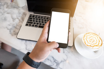 close-up on hand holding phone showing white screen on desk at coffee shop.