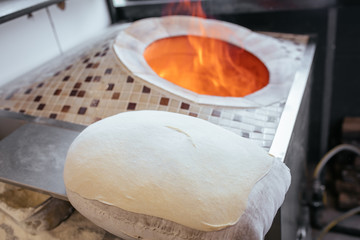 Fototapeta na wymiar Traditional turkish wood fired stone brick oven and pita or pide bread dough. This stone oven for Turkish pide or pita bread. Also known as Tandır or Tandir