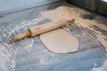 Rolling pin, dough and flour in kitchen or bakehouse