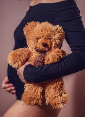 Pregnant belly and teddy bear