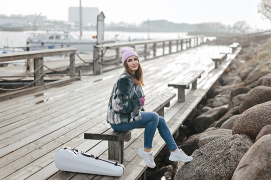 Beautiful girl with white case for violin on sea coast