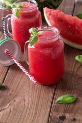 Fresh watermelon smoothie in the mason jar on wooden background. Summer, healthy organic food concept.