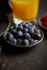 Close up on fresh blueberries placed on ceramic saucer on dark rusty table. Selective focus. Healthy breakfast ingredient.