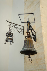 Bell and lantern on the background of the yellow wall of the monastery