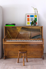Upright acoustic piano open for tuning and a chair