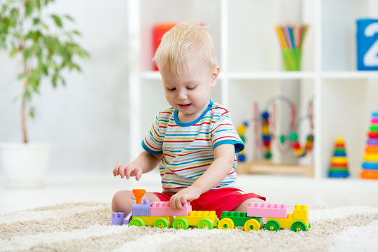 Nursery child boy plays with block toys on floor