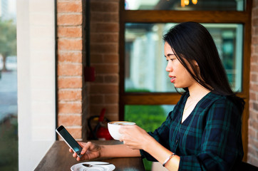 Obraz na płótnie Canvas Girl having coffee and using phone in the bar