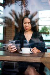 Girl having coffee and using phone in the bar