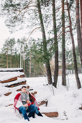 Fototapeta premium Smiling couple wrapped in a blanket and drinking tea outdoors in winter forest