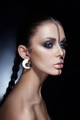 Creative makeup on woman face, beautiful big eyes. Fashion Perfect makeup, silver color band on the girl face, silver eyebrows and black brunette hair. Portrait of a woman on a dark background