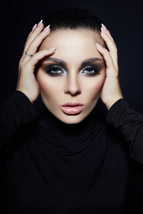 Fototapeta na wymiar Classic Smokey makeup on woman face, beautiful big eyes. Fashion Perfect makeup, expressive eyes on girl face, smooth black eyebrows, licked brunette hair. Portrait of a woman on a dark background