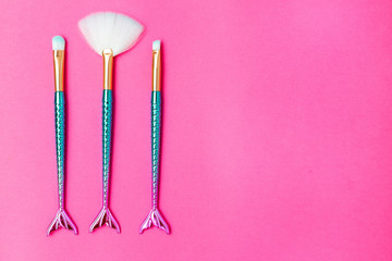 Mermaid makeup brush on bright pink background. Copy space