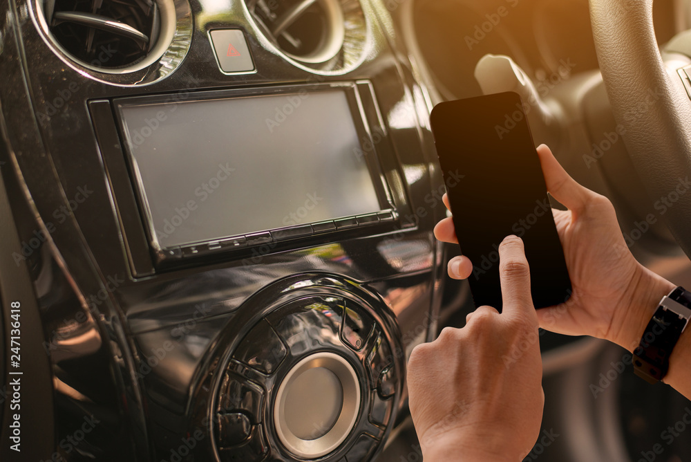 Poster using mobile phone device while driving. hands free talking and listening online music while traveli