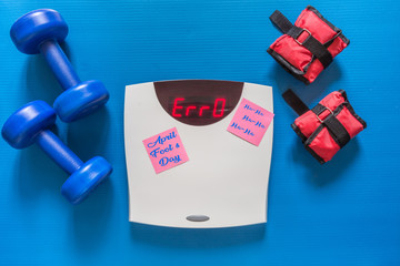 Scales with a crack and the inscription error, dumbbells on a sports rug, a rally, a joke on April 1 fool's day of laughter