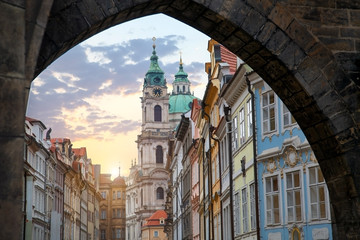 Naklejka premium view of the city of Prague through the old arch. Tourist theme. Old town in the evening with the sunset sun