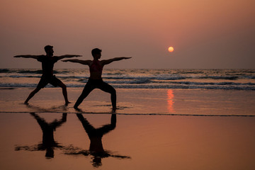 muladhara swadhisthana manipula tantra yoga on the beach man and woman meditates sitting on the sand by the sea at sunset romantic Valentine's Day.couple practicing yoga steam