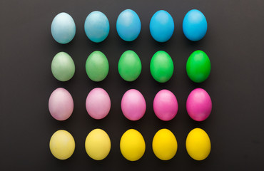 Colorful Easter eggs on black background, top view