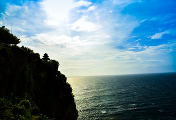 Sacred historical temple on top of the cliff abve pacific sea ocean with calm wave water and sunset background cloudy blue sky for praying zen meditating