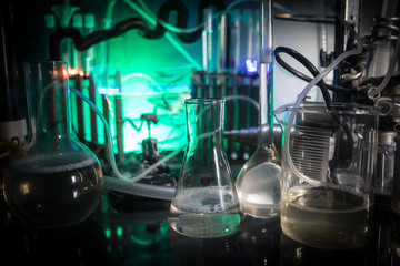 Pharmacy and chemistry theme. Test glass flask with solution in research laboratory. Science and medical background. Laboratory test tubes on dark toned background