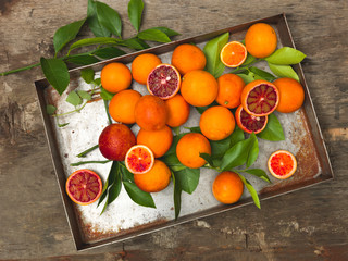 fresh, juicy blood oranges lie in an old silver pan on a wooden background