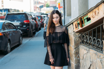 portrait of a girl, brunette, in a black dress, in the arch, in the city. posing, walking. alone in the crowd, loneliness