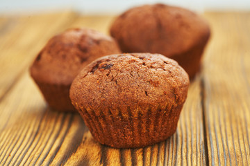 Dark chocolate dough muffin on the background of an old wooden table.