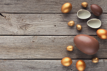 Chocolate and golden easter eggs on wooden background