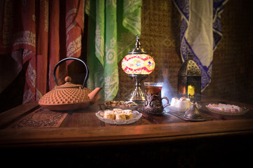 Arabian tea in glass with eastern snacks on vintage wooden surface. Eastern tea concept. Low light...