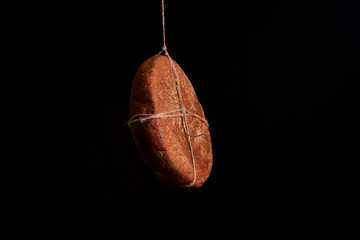 Round fresh bread hanging on a rope on a black background. Copy space