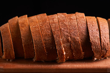 Sliced bread on a wooden table and on a black background. Selective focus