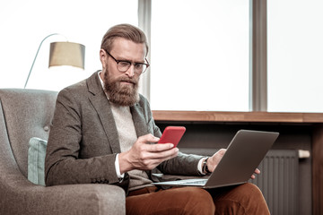 Concentrated young businessman staring at screen of his gadget