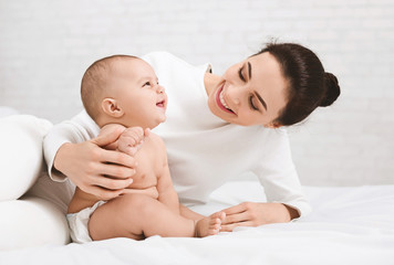 Mother playing with her baby in bedroom.