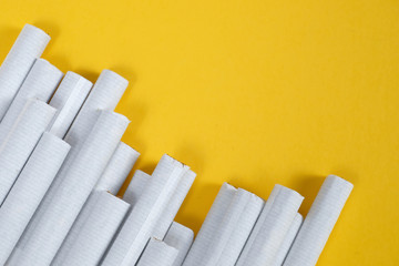 Several cigarettes carelessly lie at an angle on a yellow background. Top view. Copy space.