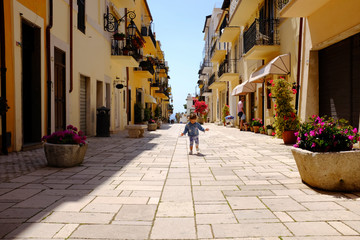 Fototapeta na wymiar A little girl runs happily in the picturesque Italian village. San Felice Circeo, Lazio, Italy