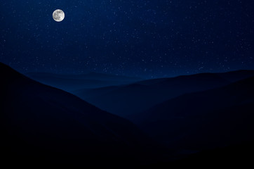 Mountain Road through the forest on a full moon night. Scenic night landscape of dark blue sky with moon. Azerbaijan