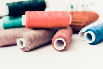 Red knitted needle pad for sewing and colored thread coils on white background with copy space for text.