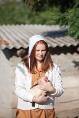 A woman in a village is holding a hen. Shooting in retro style.