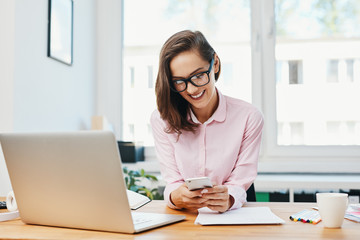 Young woman sitting in office and using phone