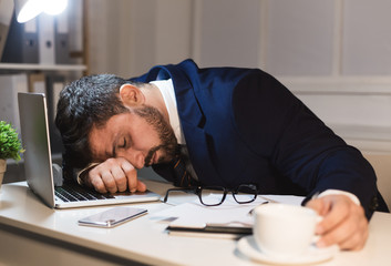 Tired businessman sleeping on laptop in the office
