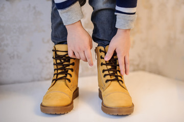 close up photo of a boy's legs in yellow leather child shoes on vintage background