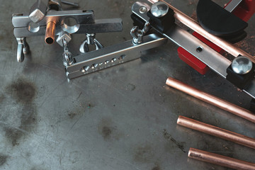 Pipes, pipe rammer and pipe bender tools on a fitter workbench background with copy space.