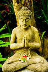 Stone buddha statue sitting meditating praying for good fortune and peaceful state of mind