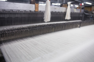 Yarn thread lines on the weaving loom machine. A loom machine for clothing or woven label. Weaving machine for garment industry. Weaving loom in textile factory.