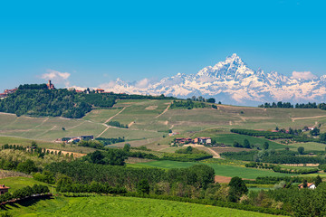 Green hills and snowy mountain peak on background in Italy.