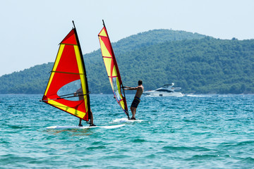 A picture of two windsurfs on the sea during the hot summer day. Pictured in Croatia. 