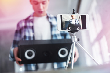 Handsome student filming video about birthday presents using photo stand