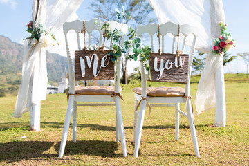 Wedding Me and You signs on chairs standing in the woods.