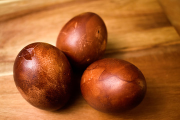 Close up naturally onion painted red Easter eggs with one cracked egg on a wooden table. Easter holiday concept.